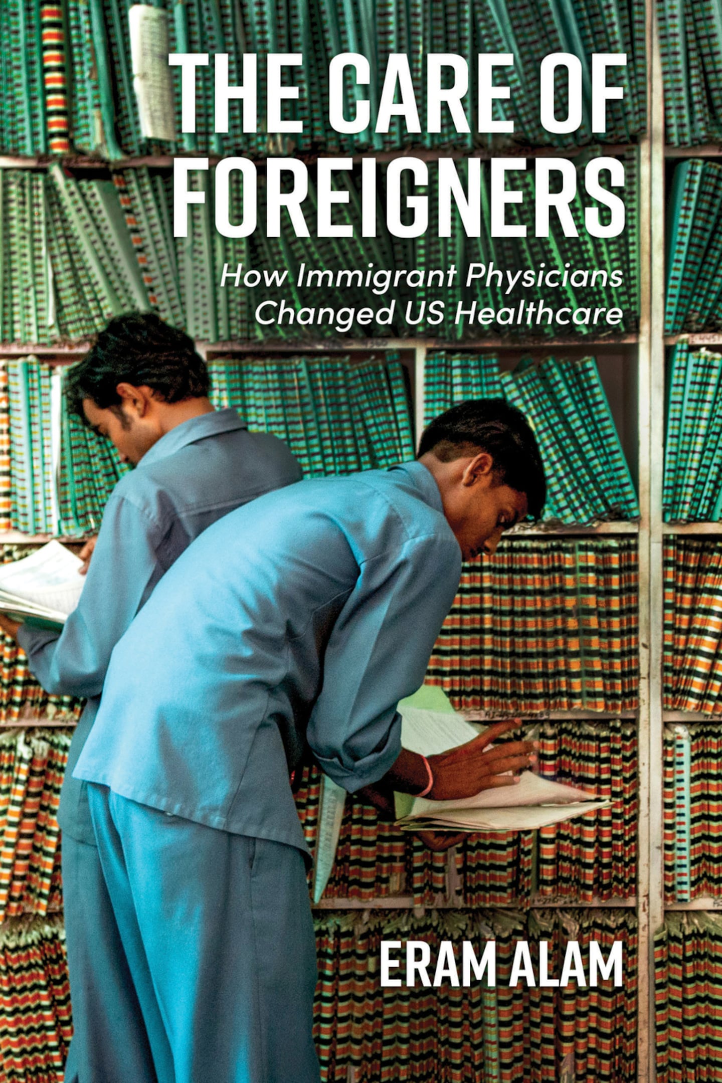 A book jacket showing two people wearing blue hospital-style scrubs. They are standing in front of a wall of with files of medical records. In white lettering at the top of the cover it says, "The Care of Foreigners." Under that in smaller letters, it says "How Immigrant Physicians Changed US Healthcare." On the bottom is shows the author's name, Eram Alam.