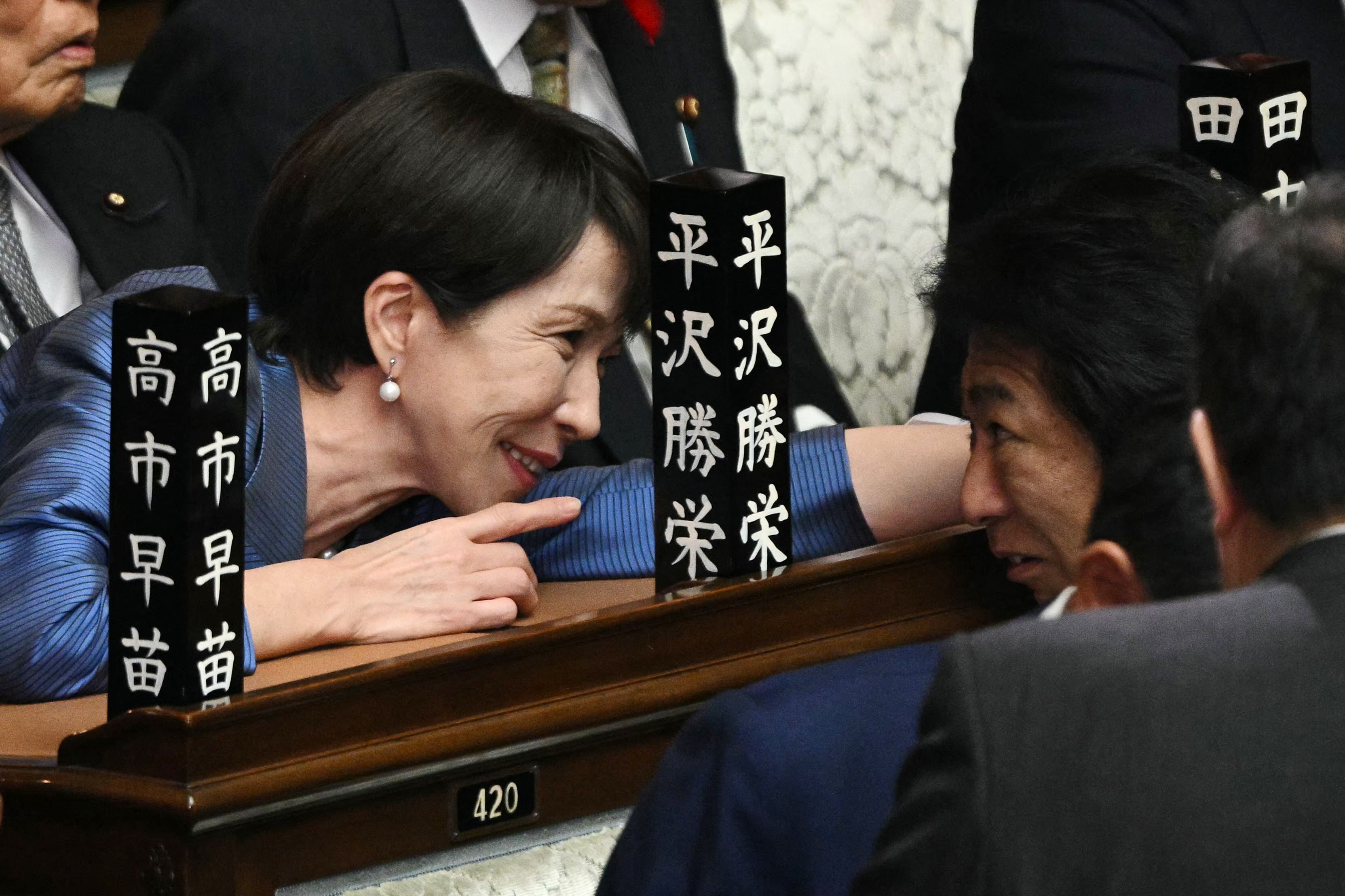 Liberal Democratic Party (LDP) president Sanae Takaichi speaks to a lawmaker before the start of an extraordinary session of the lower house of parliament in Tokyo on 21 October 2025