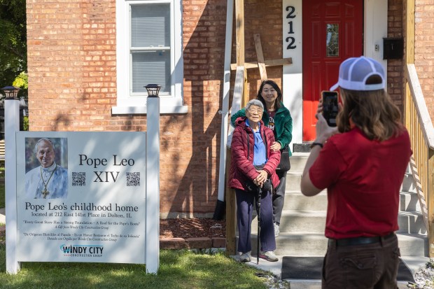 Tour guide Tucker Privette takes a photo of Grace Hornback and her mother Anita Lim in front of Pope Leo XIV's childhood home during a tour in Dolton on Saturday, Sept. 6, 2025. (Troy Stolt for the Daily Southtown)