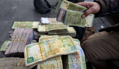 A currency trader sits by a stack of Syrian pounds at his street stall in Damascus, 14/1/2025 (Louai Beshara/AFP)