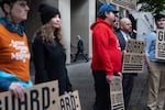 FILE - Protesters hold signs reading "Guard: Go Home" while people make their way into the Mark O. Hatfield United States Courthouse on Friday, Oct. 3 in Portland, Ore. 