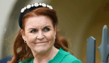 Sarah Ferguson wearing a green jacket and black headband looking to the side and smirking