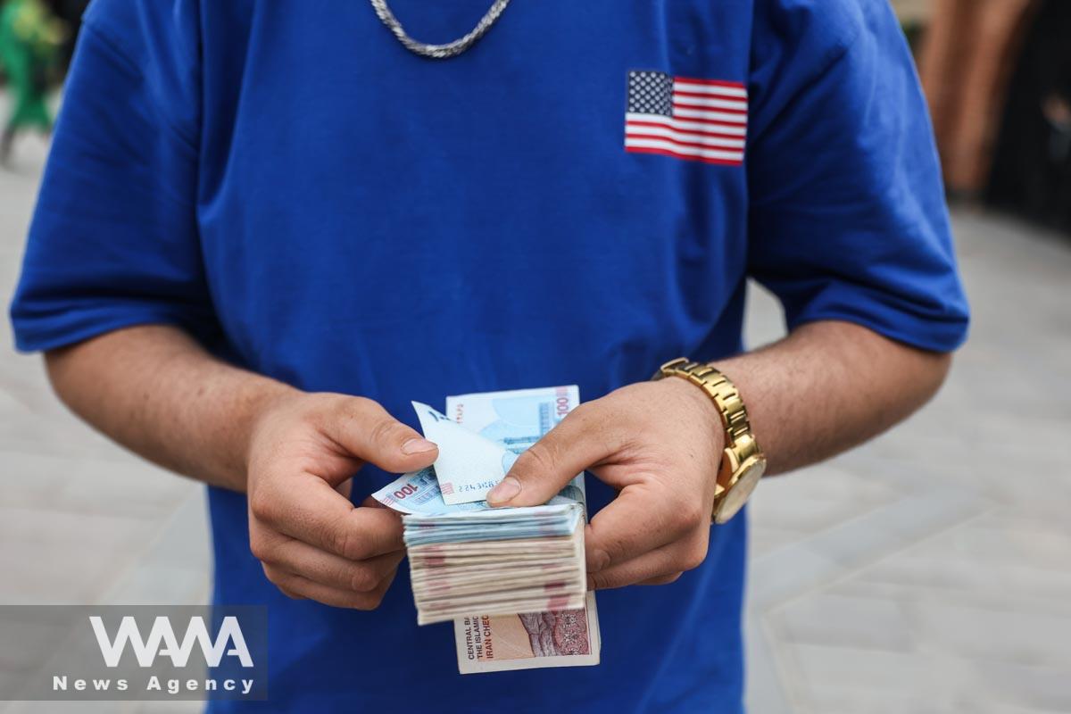 A currency dealer holds Iranian Rial bills at the Tehran Bazaar in Tehran