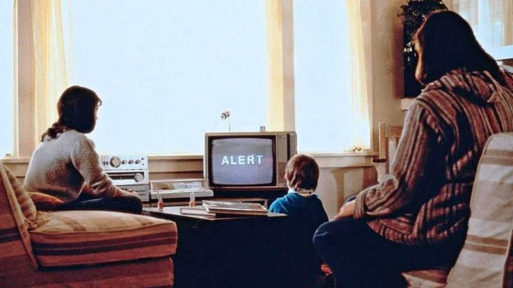a family looks at a TV set with the words alert on it in the film testament