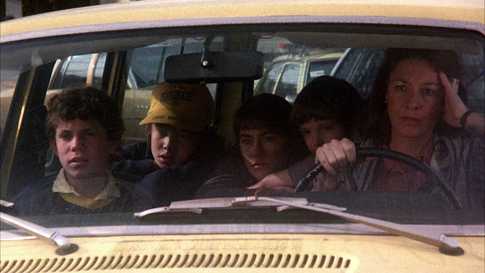a woman and a group of children sit in a car in the film testament