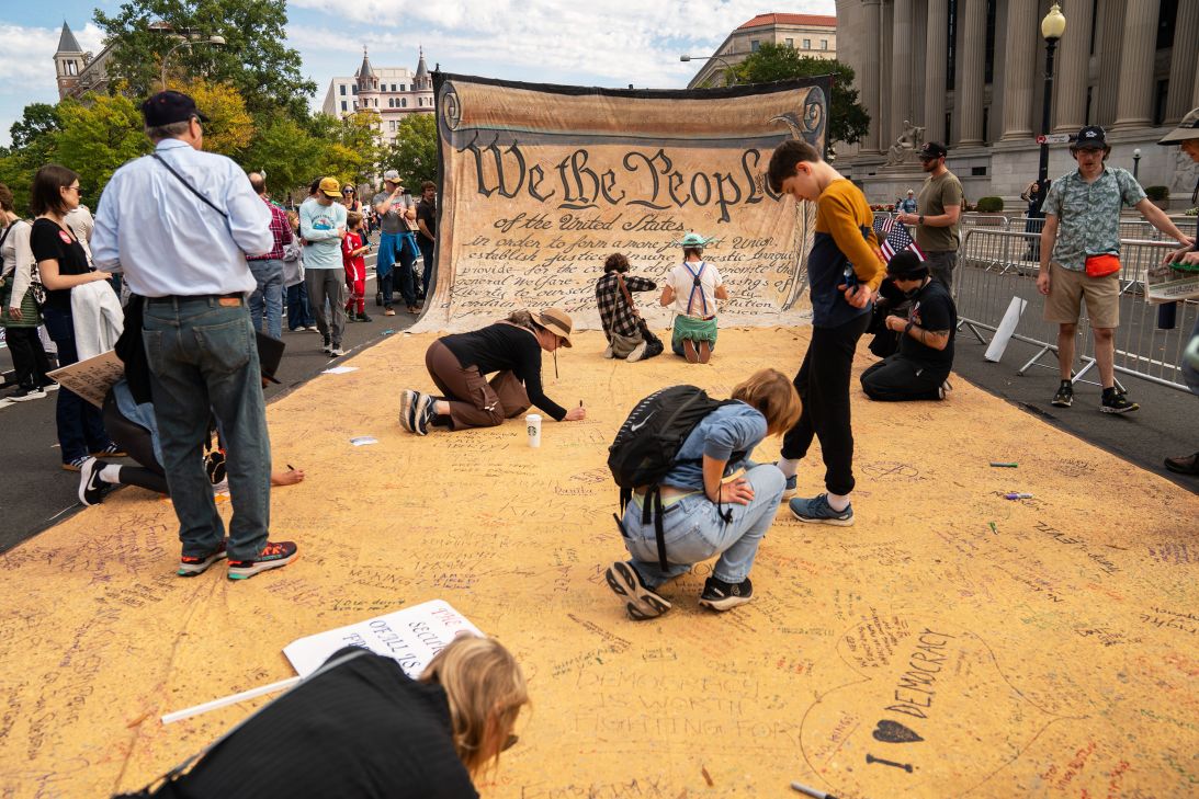 Attendees sign a banner representing the US Constitution during a