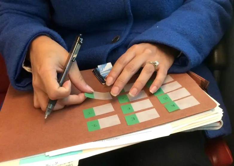 Hands on top of a folder with documents lay out stick tabs for organization.