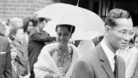 Queen Sirikit holds an umbrella in a black and white photograph
