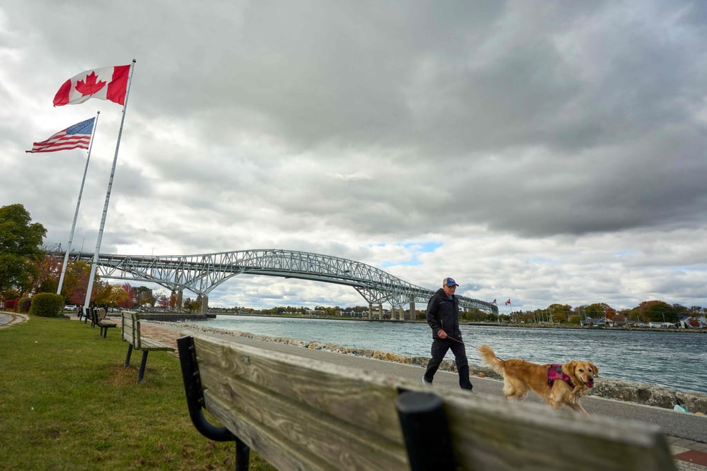 US and Canadian flags fly as a man walks his dog along the St Clair River backdropped by the Blue Water Bridge border crossing in Point Edward, Ontario, on October 24. Photo: AFP US and Canadian flags fly as a man walks his dog along the St Clair River backdropped by the Blue Water Bridge border crossing in Point Edward, Ontario, on October 24. Photo: AFP