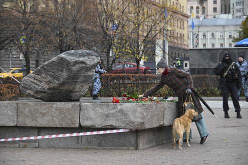 Une femme dépose des fleurs sur le monument, sous la surveillance de la police, à Moscou, le 29 octobre 2025.
