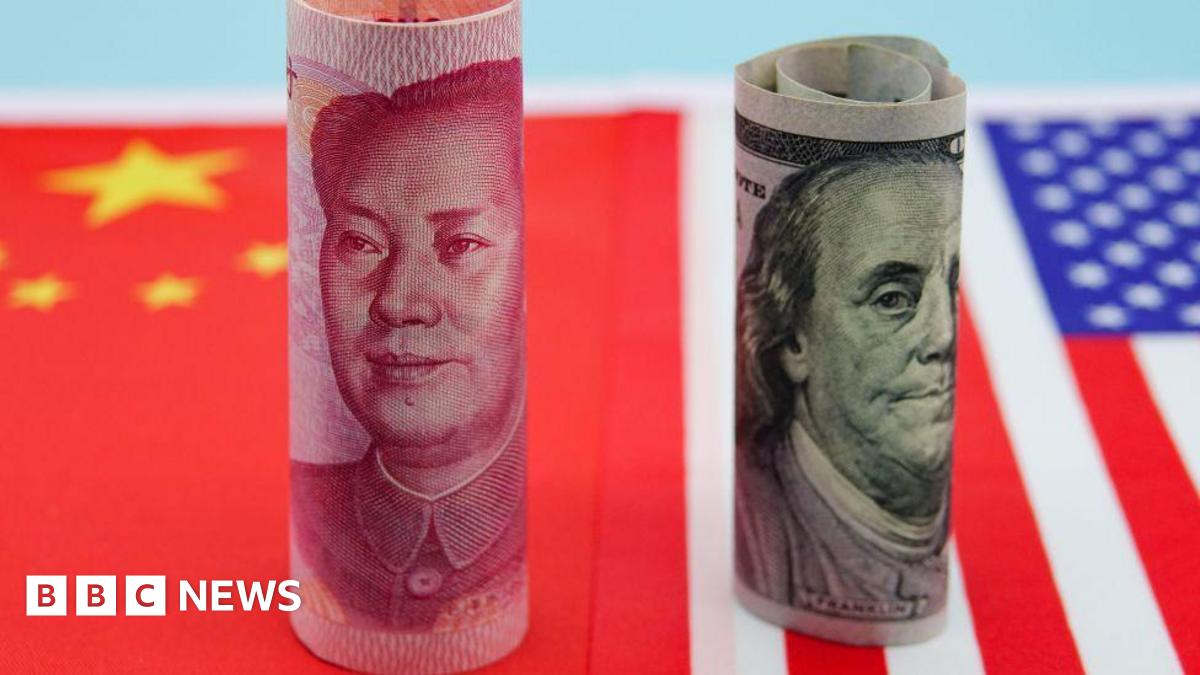 Banknotes from China and US are rolled up and standing upright on flags of both countries