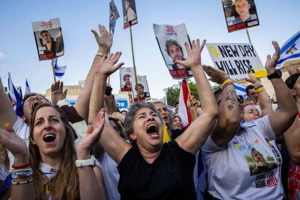 People react as they watch a live broadcast of hostages...