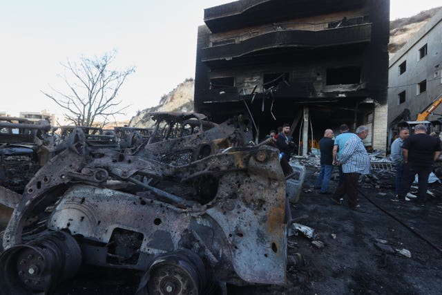 People gather at a site that sold heavy machinery, where a large number of vehicles were destroyed in Israeli air strikes, in the southern village of Msayleh, Lebanon