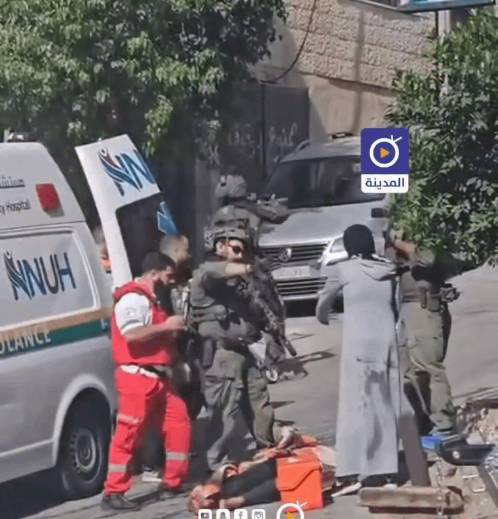 An Israeli soldier assaults a woman as she tries to prevent occupation forces from seizing her husband's body after he was shot by Israeli troops during their raid on the city of Nablus.