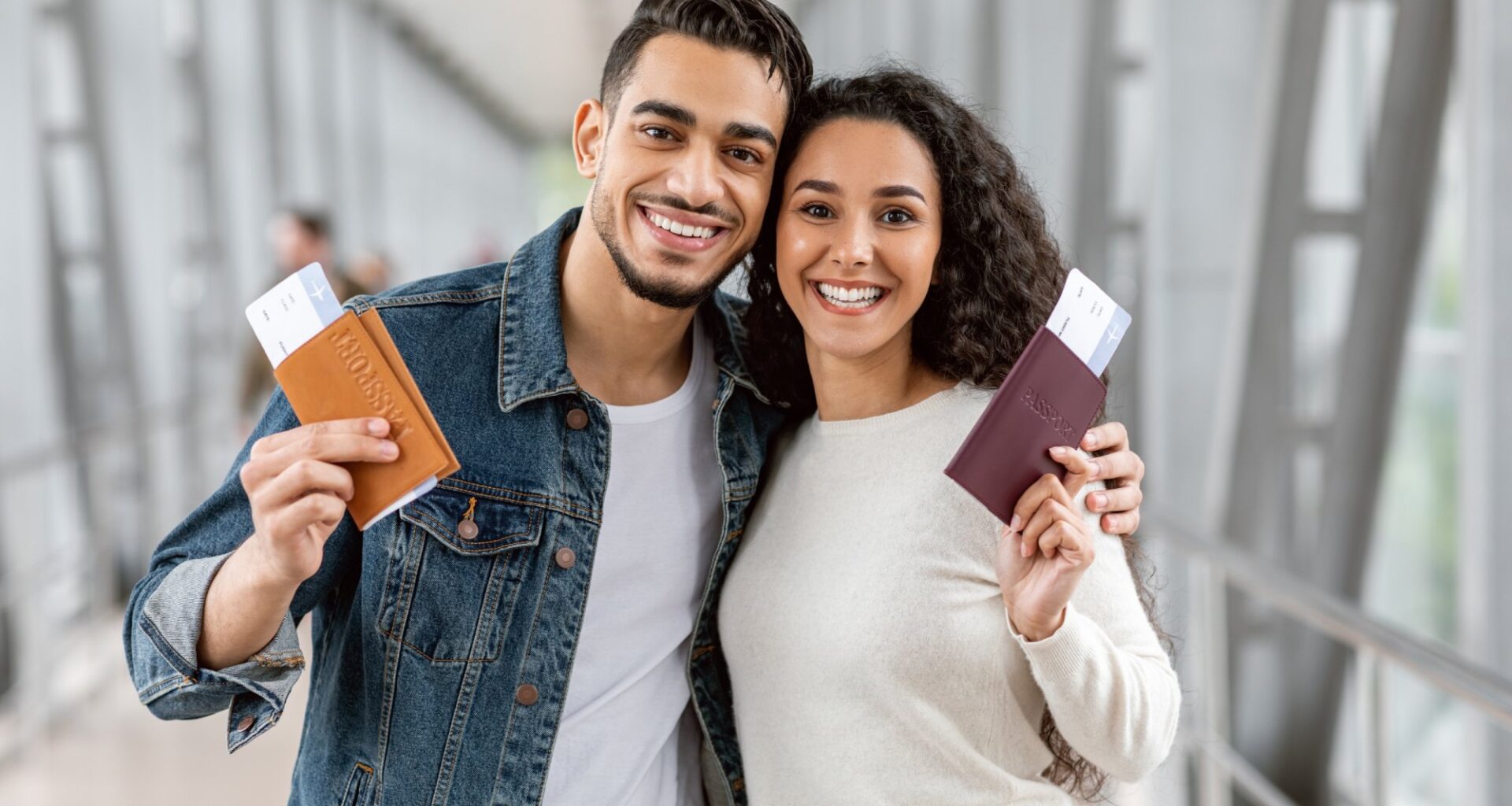 A Couple holding passports at an airport with boarding passes inside.