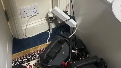 A number of large batteries charging on the floor connected straight through the socket.