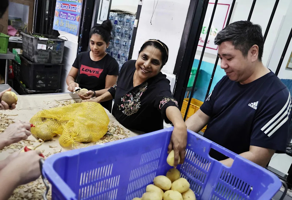 Ms Latha Govindasamy (centre) and volunteers peeling potatoes in preparation for Deepavali Fiesta 2025.