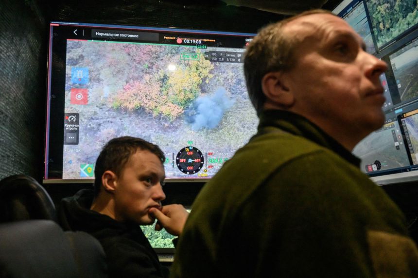 A screen shows Ukrainian soldiers watching a fatal drone strike on a Russian soldier who was attempting to cross a field north of Izyum, at a drone command centre in an undisclosed location of Ukraine, on October 7, 2025.