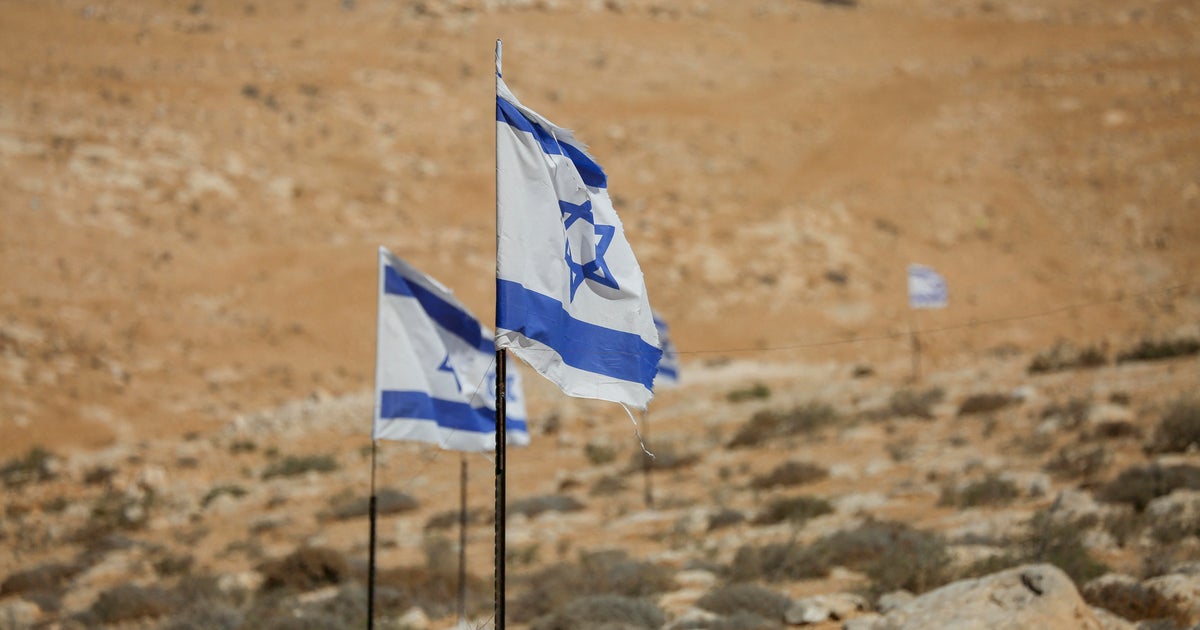 Israeli flags fly above olive trees in the village of Hawara, in the Masafer Yatta area, south of Hebron, West Bank, on Oct. 7, 2025.