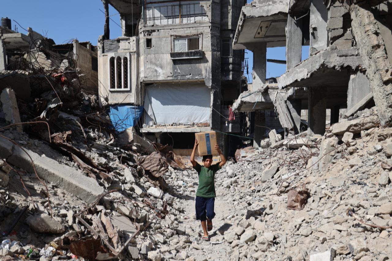 A displaced Palestinian boy carries a box of emergency supplies provided by the World Food Programme (WFP) after receiving it from an aid distribution point at the Nuseirat refugee camp in the central Gaza Strip, on Oct. 19, 2025. (AFP Photo)