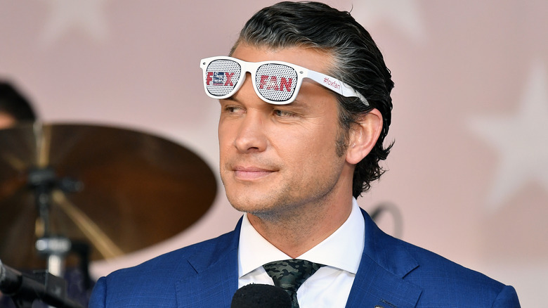 Pete Hegseth looking smug in a suit and 