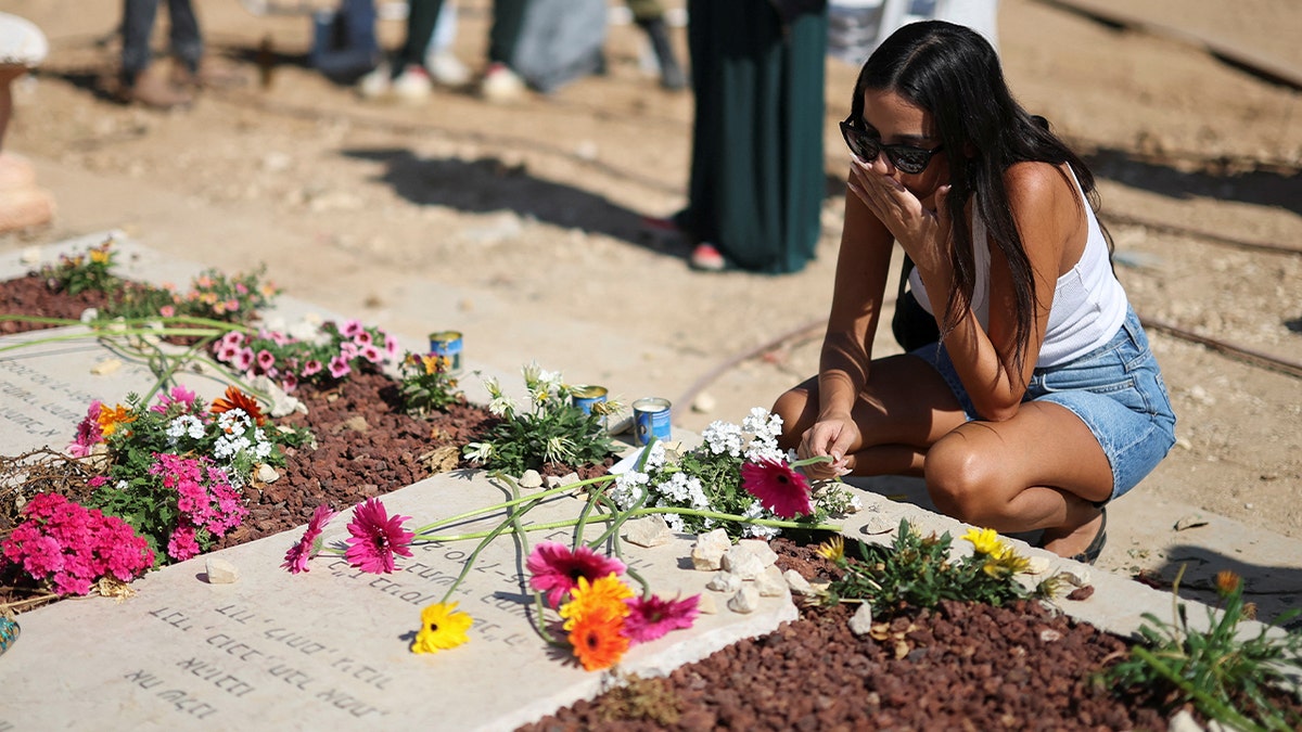 Woman kneels by a memorial site