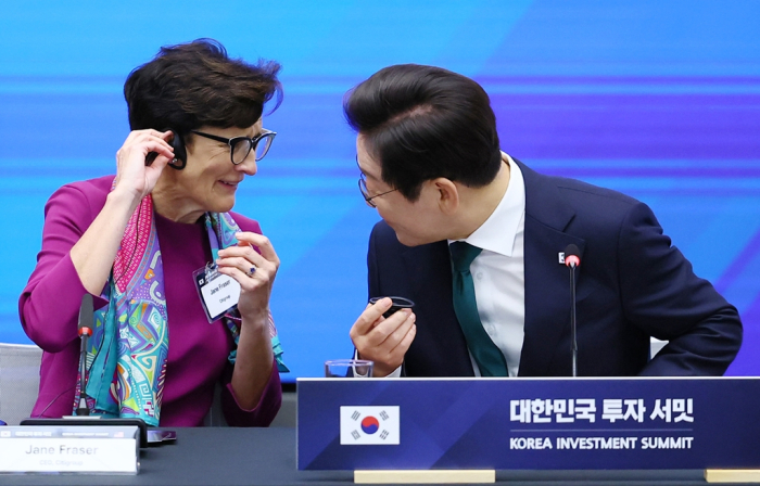 President Lee Jae Myung (right) attaches a translation device with the help of Citigroup Chairwoman Jane Fraser at the Korea Investment Summit held at the New York Stock Exchange on Sept. 25, 2025
