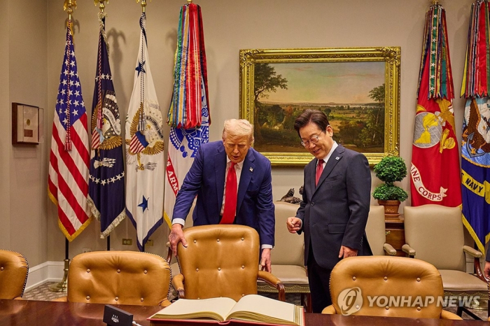 South Korean President Lee Jae Myung is guided by US President Donald Trump as he prepares to sign the guestbook ahead of their summit at the White House on Aug. 25, 2025