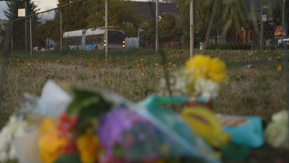 A bus in the background is featured while memorial flowers are blurry in the foreground