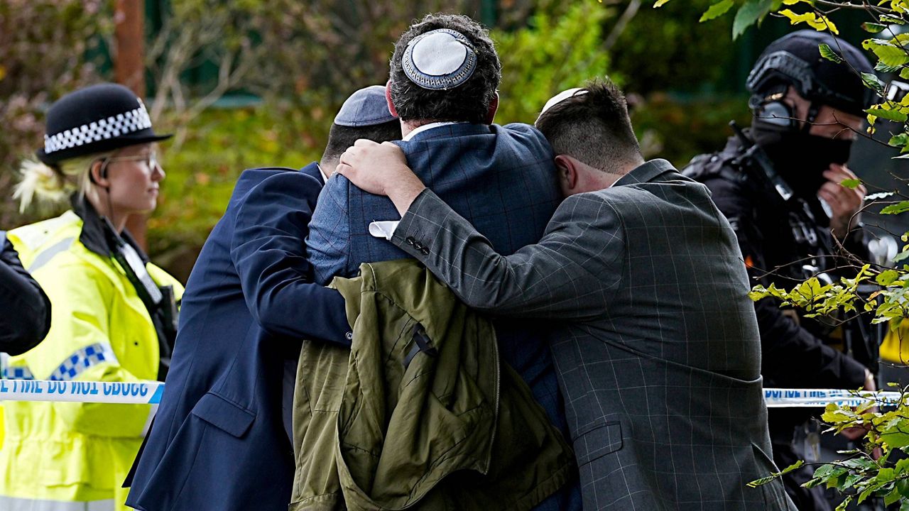 Members of the Jewish community comfort each other near to the Heaton Park Hebrew Congregation synagogue, in Crumpsall, Manchester, England, Thursday, Oct. 2, 2025 after Police reported that two people were killed and three others were seriously injured in a synagogue attack in northern England. (Peter Byrne/PA via AP)