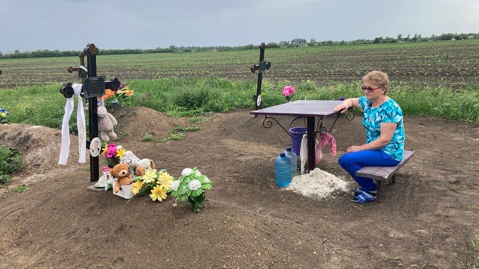 A woman sits at the grave of her 8-year-old grandson, Ivan. She also lost both of her children and her husband in the Russian strike