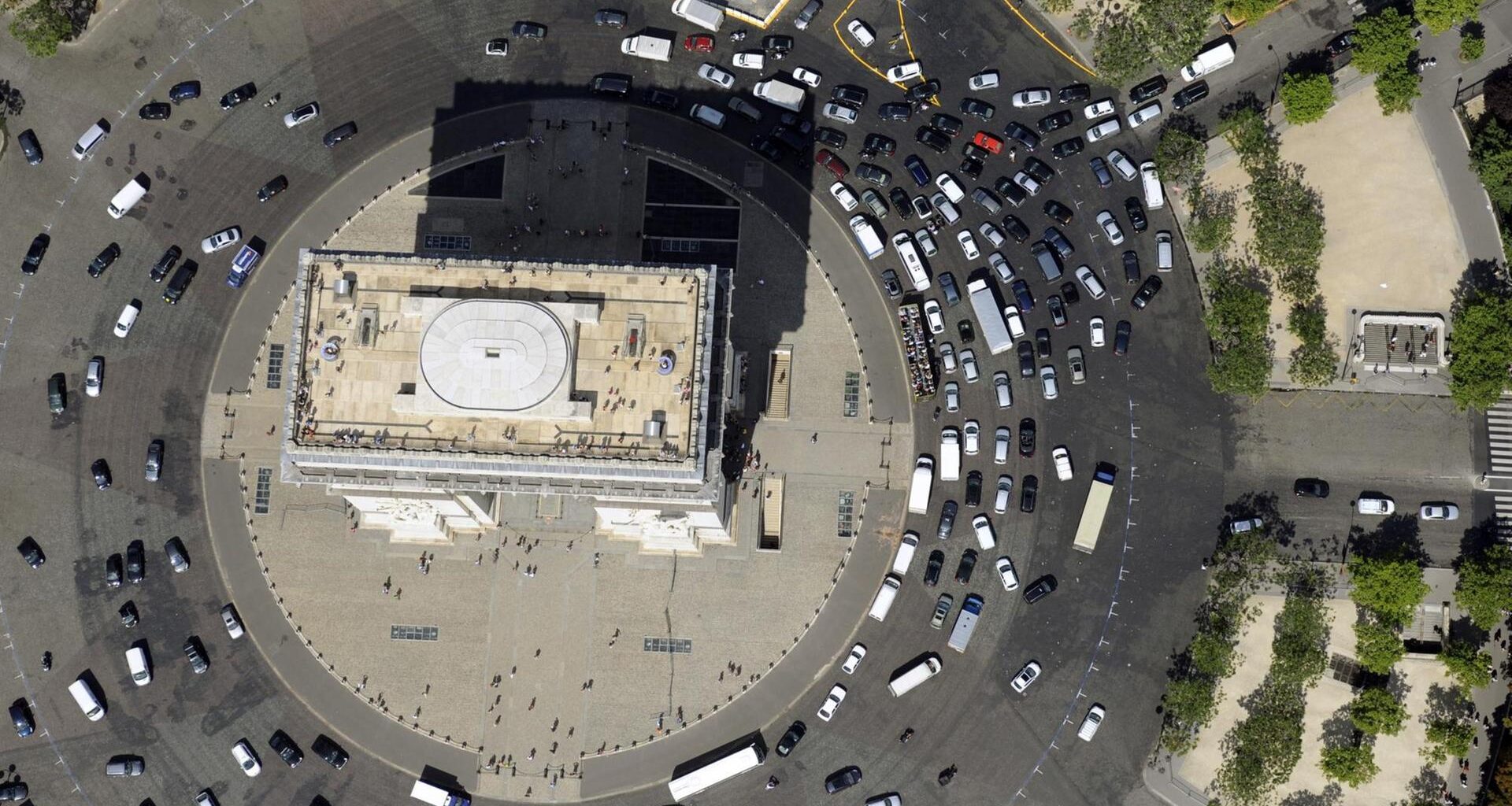 Senkrechter Blick aus der Luft: Autos fahren im Kreis um den Arc de Triomphe herum.