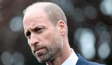 Prince William wearing a white shirt and blue jacket looking stern