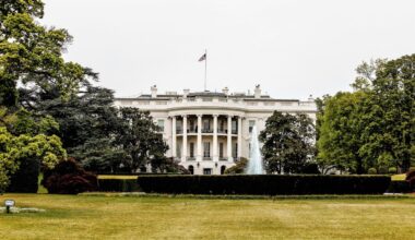 A photo of the White House, surrounded by trees and a sprawling green lawn.