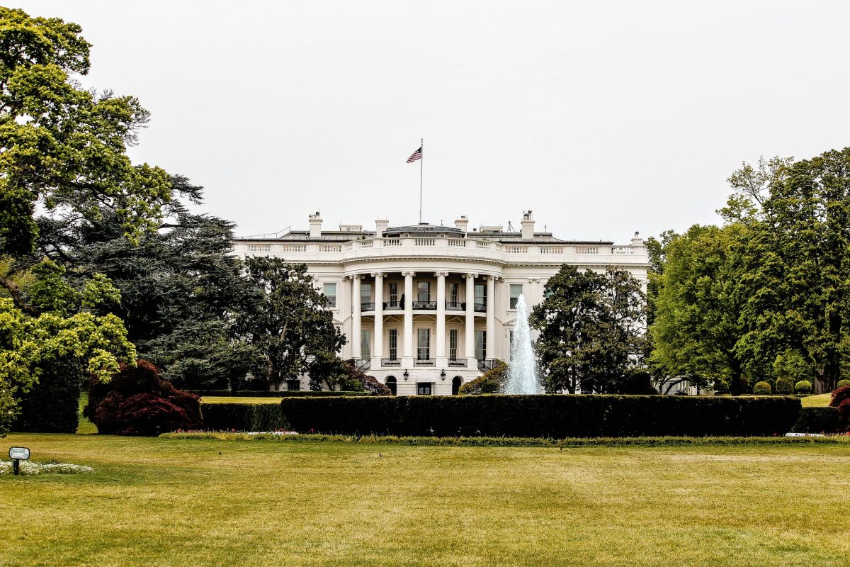 A photo of the White House, surrounded by trees and a sprawling green lawn.