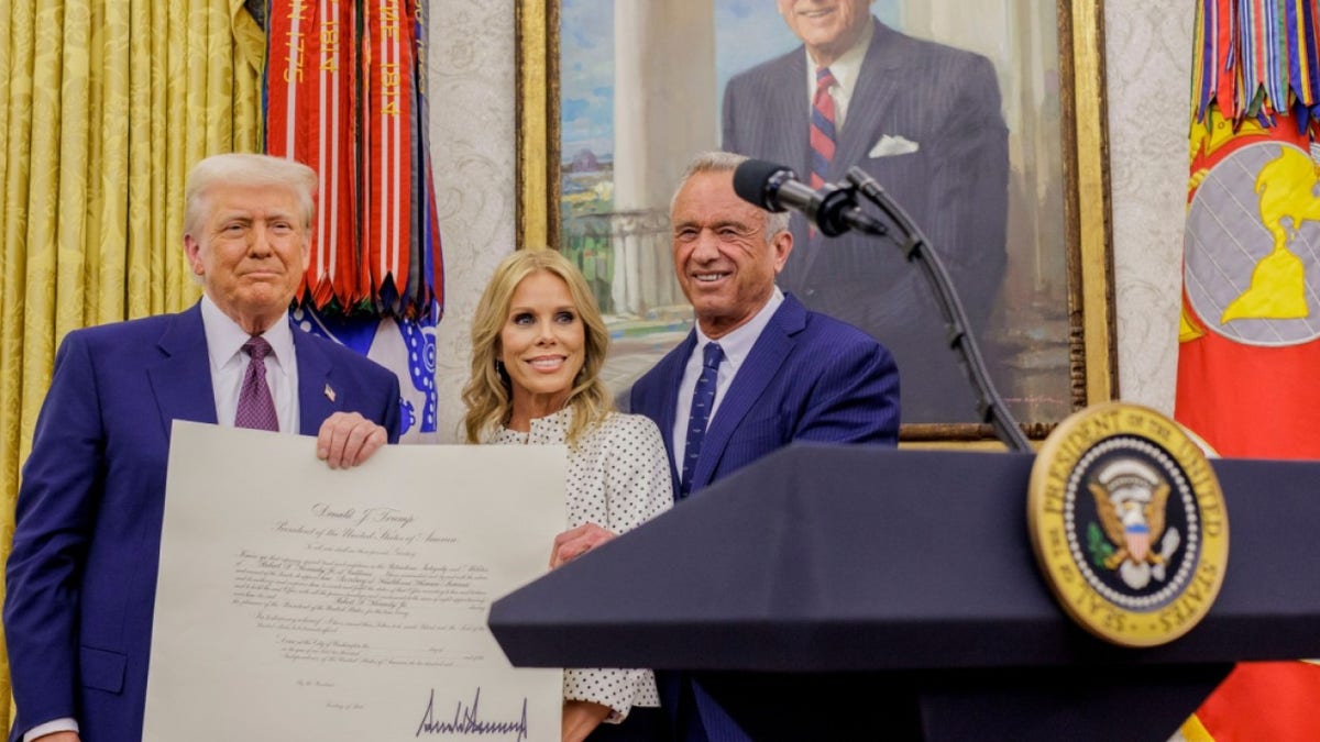 President Donald Trump, Robert F. Kennedy, Jr., and Cheryl Hines stand together in the White House.