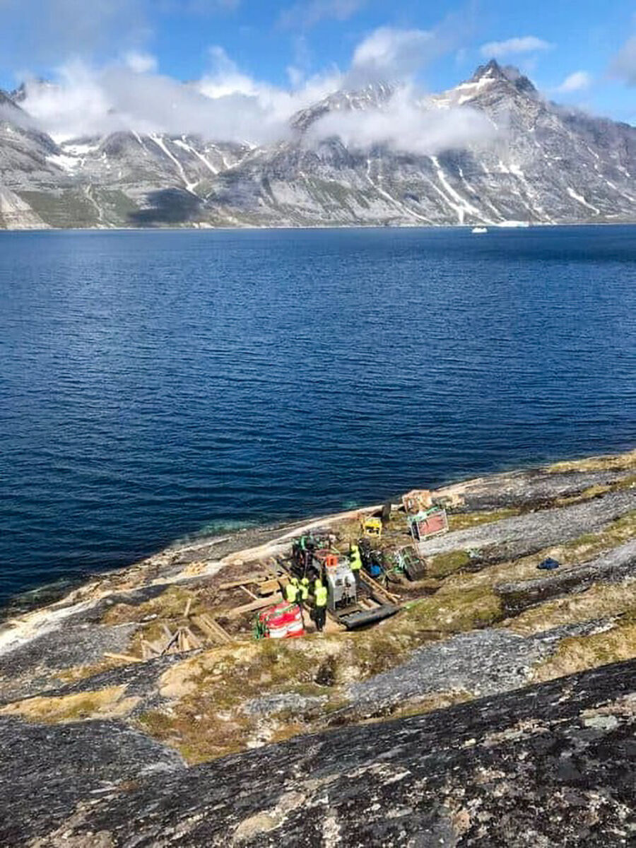 Workers%20on%20drill%20pad%20near%20rocky%20shore%20beside%20ocean%20and%20mountains%2E