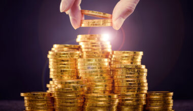 Gold coins being stacked with a hand taking some away