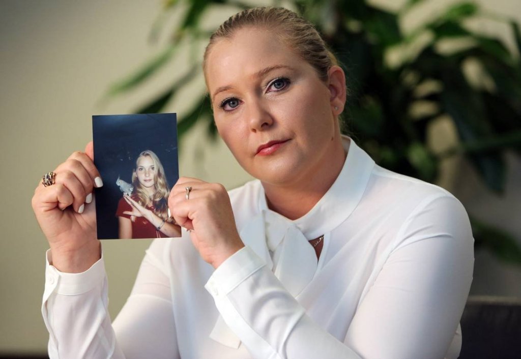 Virginia Giuffre holding up a photo of herself as a teen