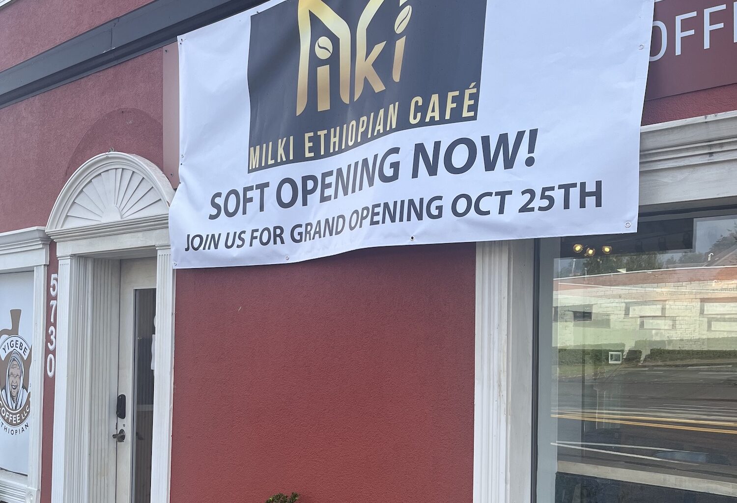 Milki Ethiopian Cafe opening announcement on a temporary sign, sitting over the more established Yigebe Coffee sign.