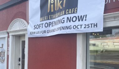 Milki Ethiopian Cafe opening announcement on a temporary sign, sitting over the more established Yigebe Coffee sign.