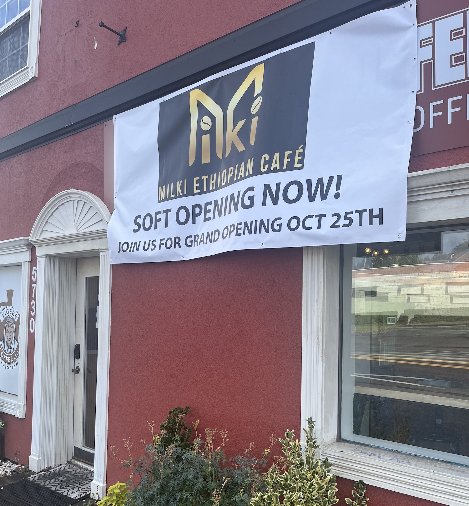 Milki Ethiopian Cafe opening announcement on a temporary sign, sitting over the more established Yigebe Coffee sign.