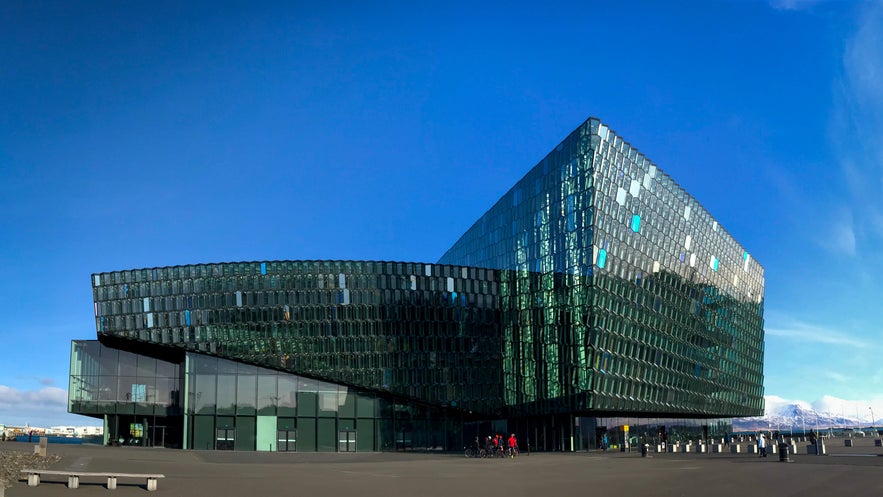 Exterior view of Harpa Concert Hall in Reykjavik with its geometric glass facade reflecting the blue sky.