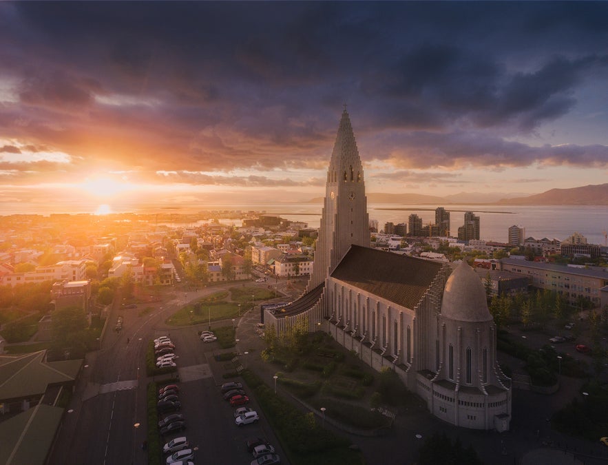 Aerial view of Hallgrimskirkja church in Reykjavik at sunset with the city and ocean in the background.