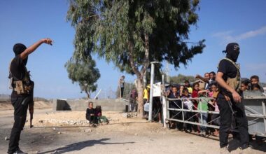 Palestinian militants wearing bandanas showing the name of Izzedine al-Qassam Brigades, armed wing of Hamas, stand guard before arrival of ICRC vehicles in central Gaza Strip, Oct. 13, 2025. (AFP Photo)