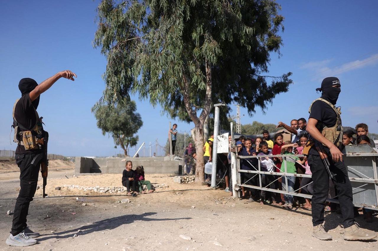 Palestinian militants wearing bandanas showing the name of Izzedine al-Qassam Brigades, armed wing of Hamas, stand guard before arrival of ICRC vehicles in central Gaza Strip, Oct. 13, 2025. (AFP Photo)