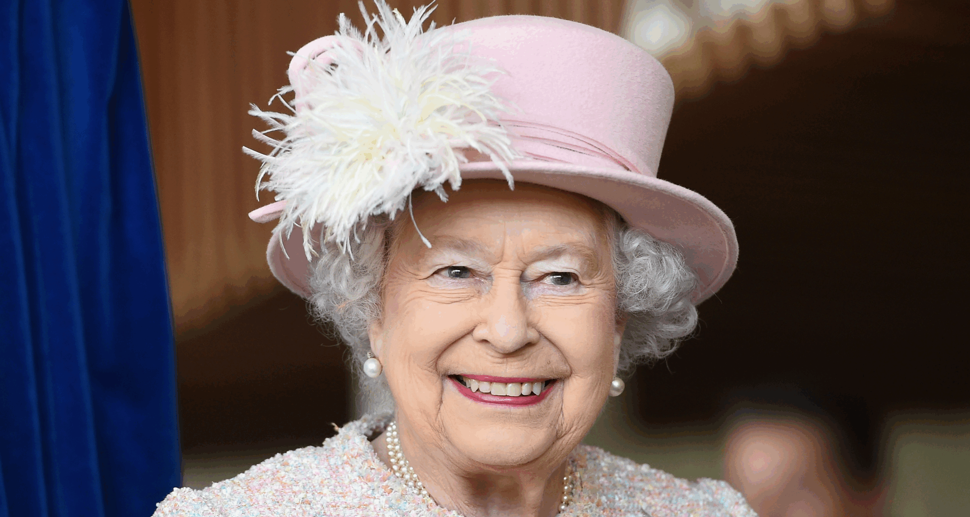 Queen Elizabeth wearing a pink hat and coat smiling