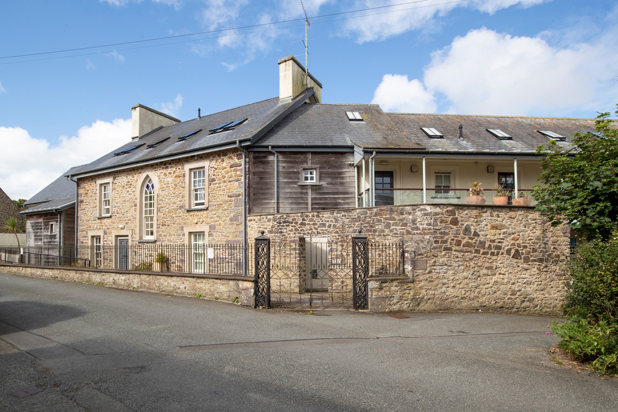 Apartment building in St Davids, Pembrokeshire, with stone and wooden exteriors, a balcony, and a wrought-iron gate, for sale at £275,000.