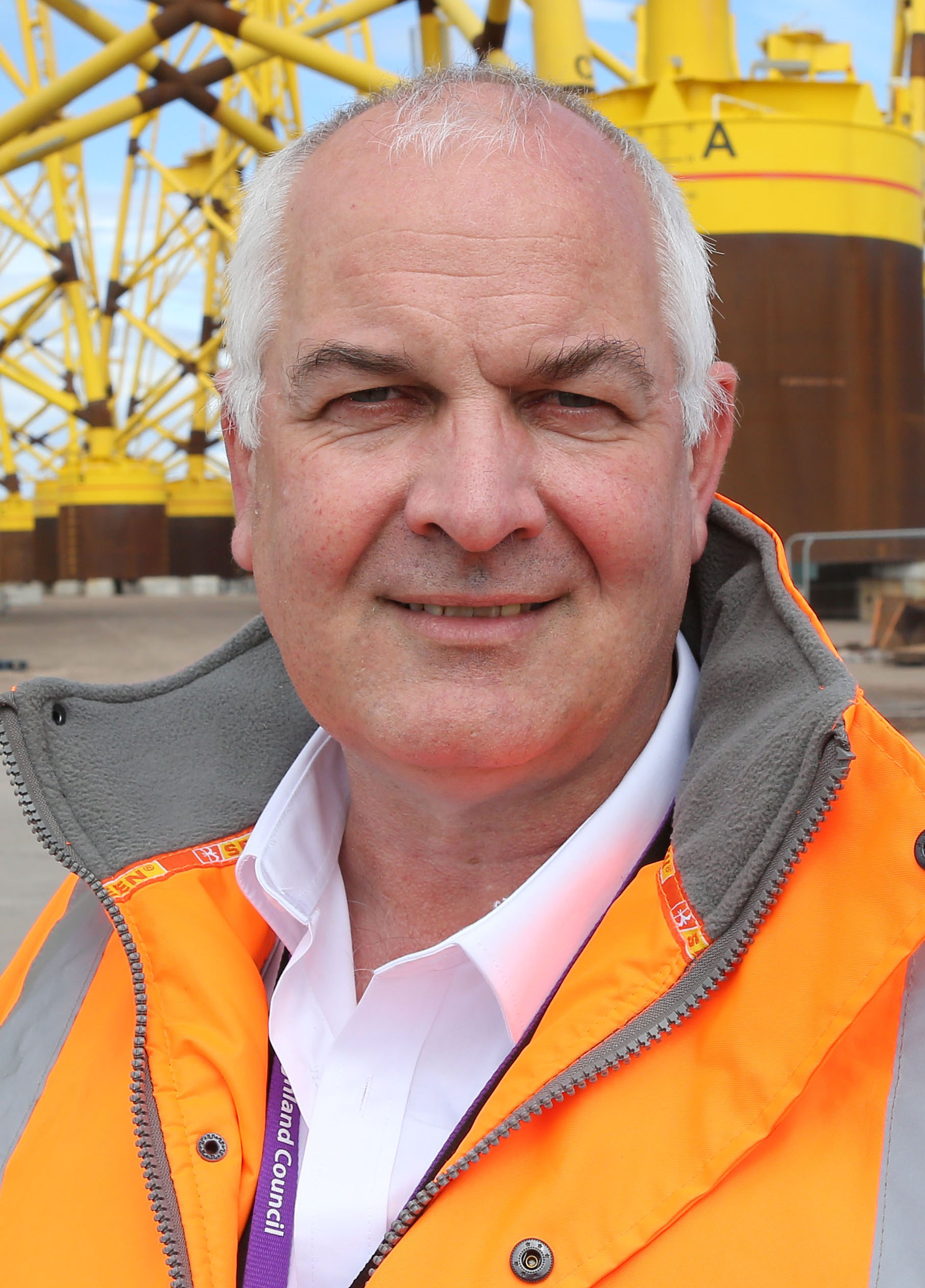 Highland council leader Raymond Bremner smiling in an orange safety jacket.