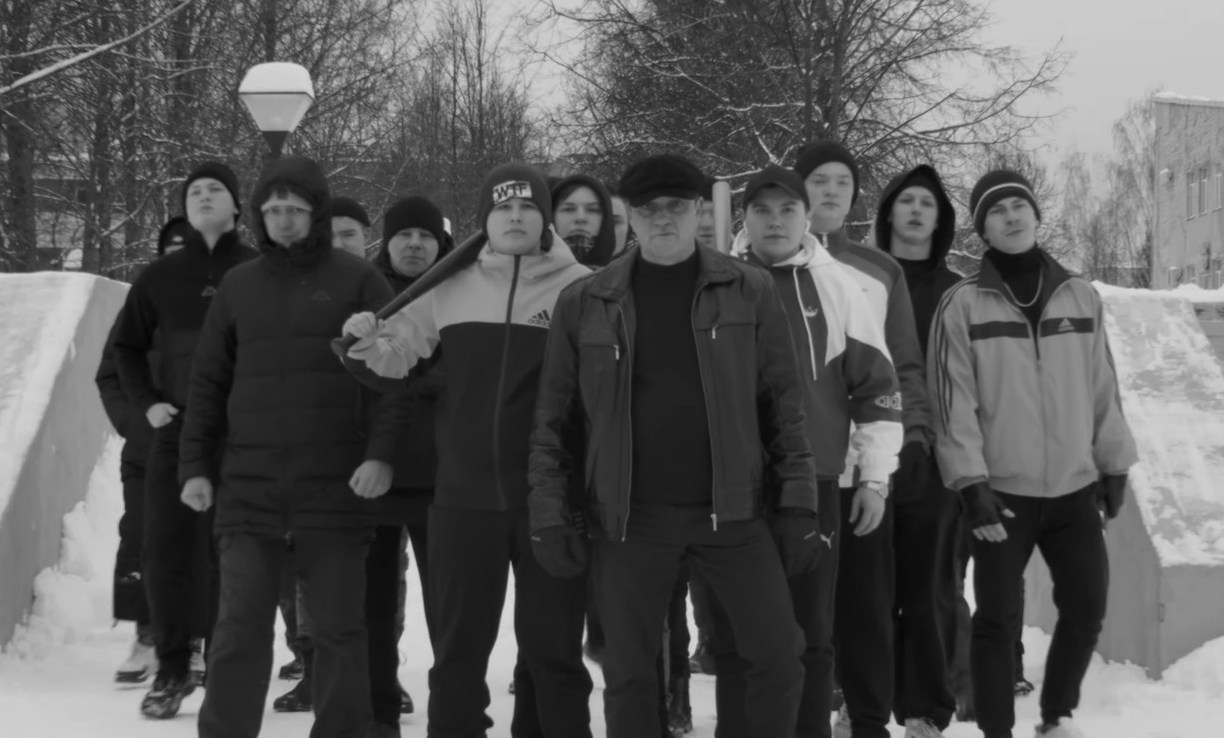 A black and white image of a group of men standing in the snow, from the music video "ШЫП ЛИЙ - Кӧ улам".